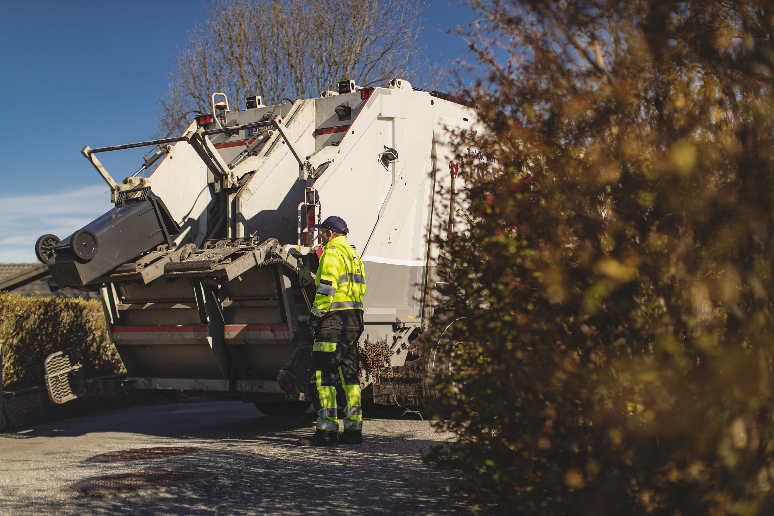 En renovatør tømmer en avfallsbeholder i bilen