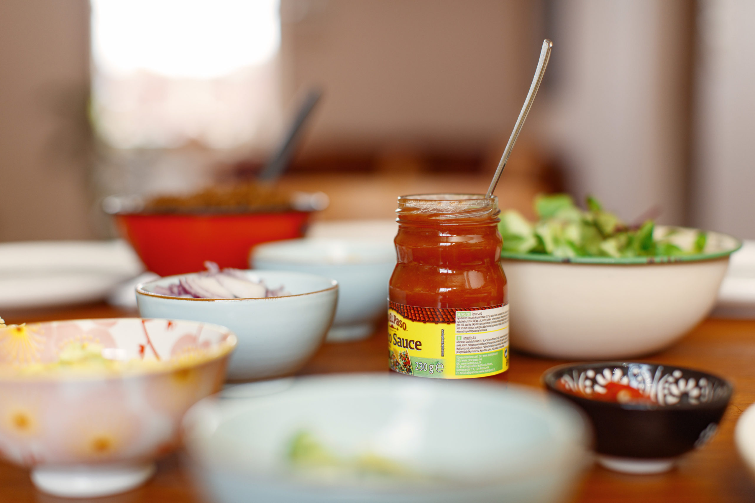 Forskjellige skåler og glass med tacotilbehør på et spisebord