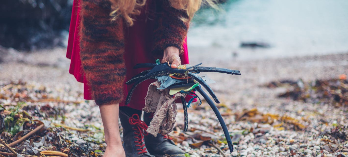 Bilde av en person som rydder avfall på en strand