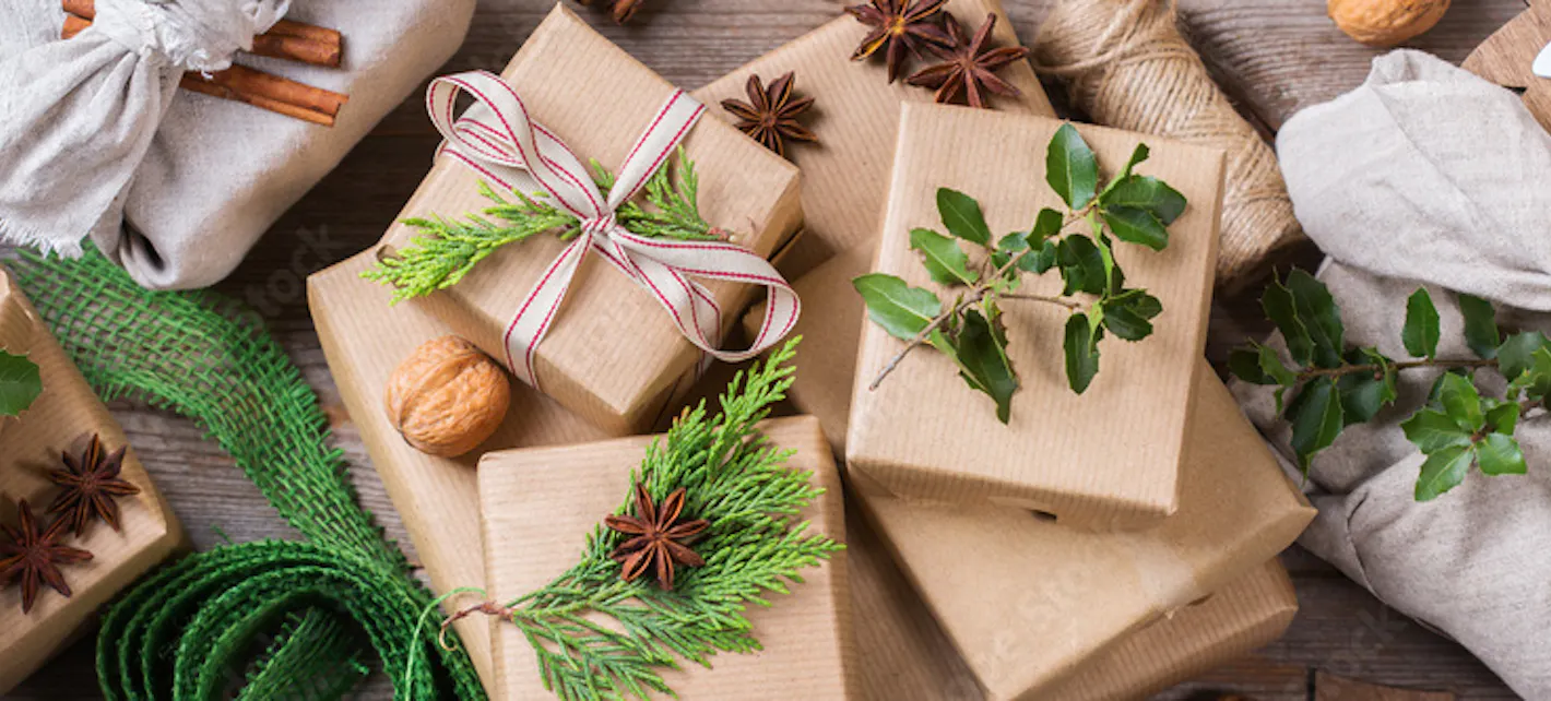 Bilde av julegaver som er pakket inn med gråpapir og pynt fra naturen, som grener og nøtter