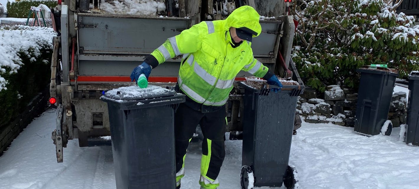 HIM-renovatør tømmer avfallsbeholdere i snøvær