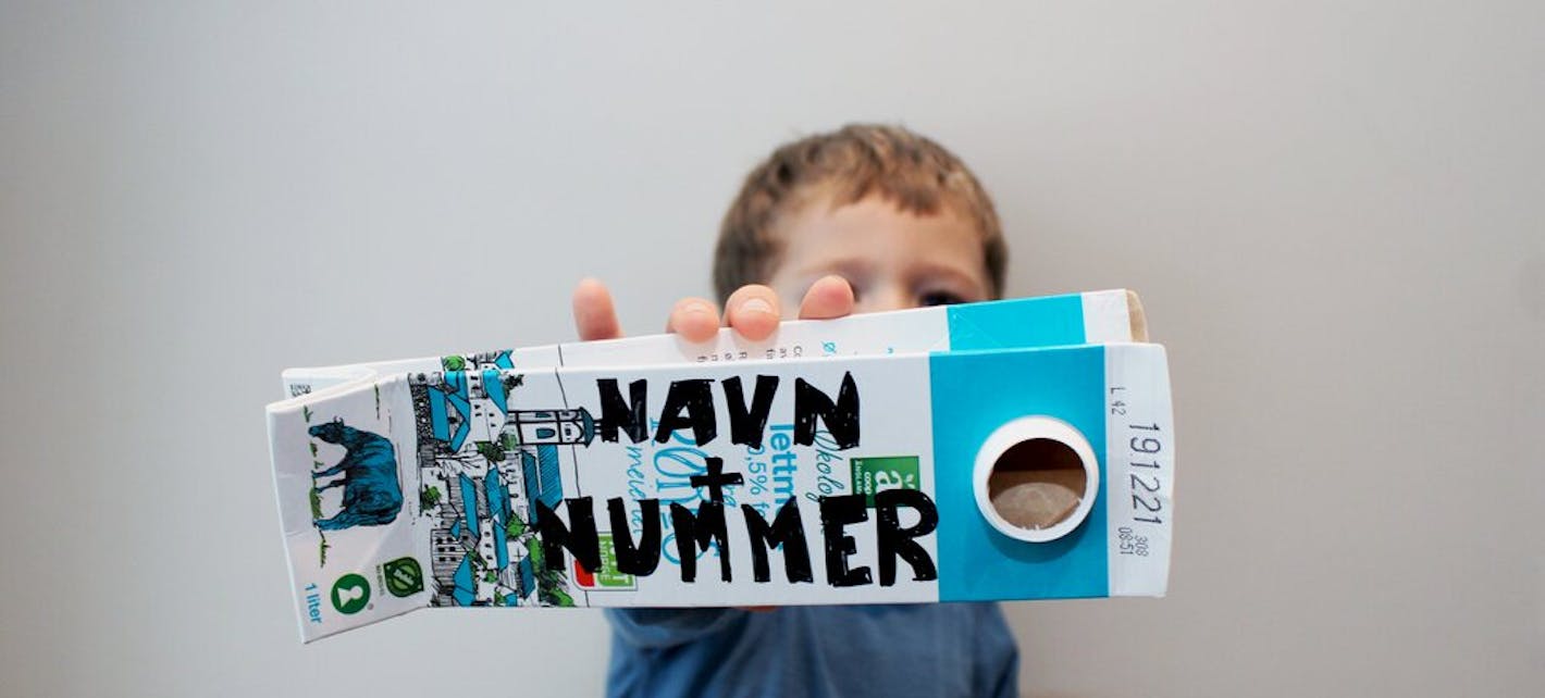 Barn holder frem en melkekartong der det står skrevet navn pluss nummer