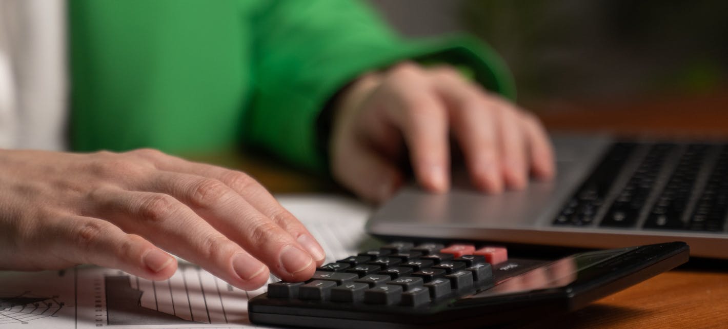 To hender som jobber på en kalkulator og et tastatur