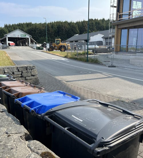 Avfallsbeholdere på rekke på Årabrot miljøpark. I bakgrunnen rampen, Affi og nybygg.