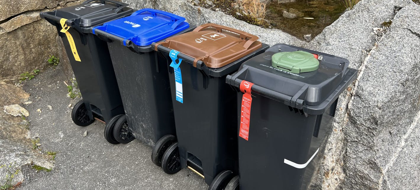 Avfallsdunker fra HIM med merkelapper hengt på i gult, blått og rødt.