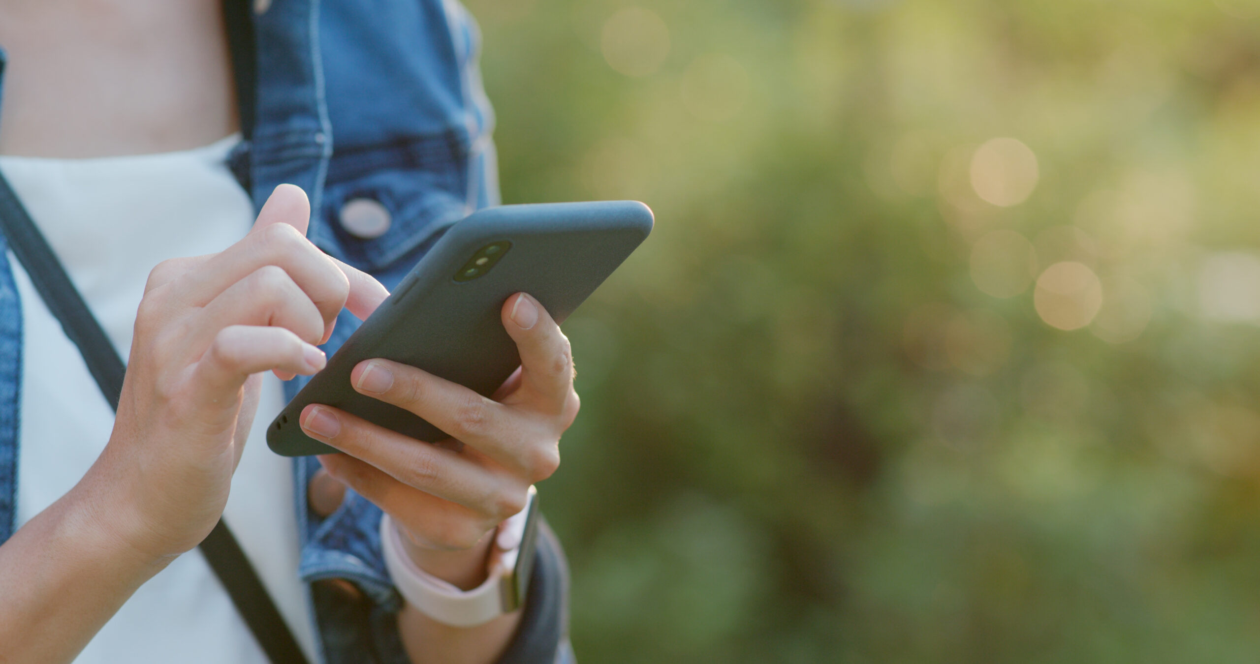 En person ses i utkanten av bildet, og taster på en mobil. Det er grønn bakgrunn.