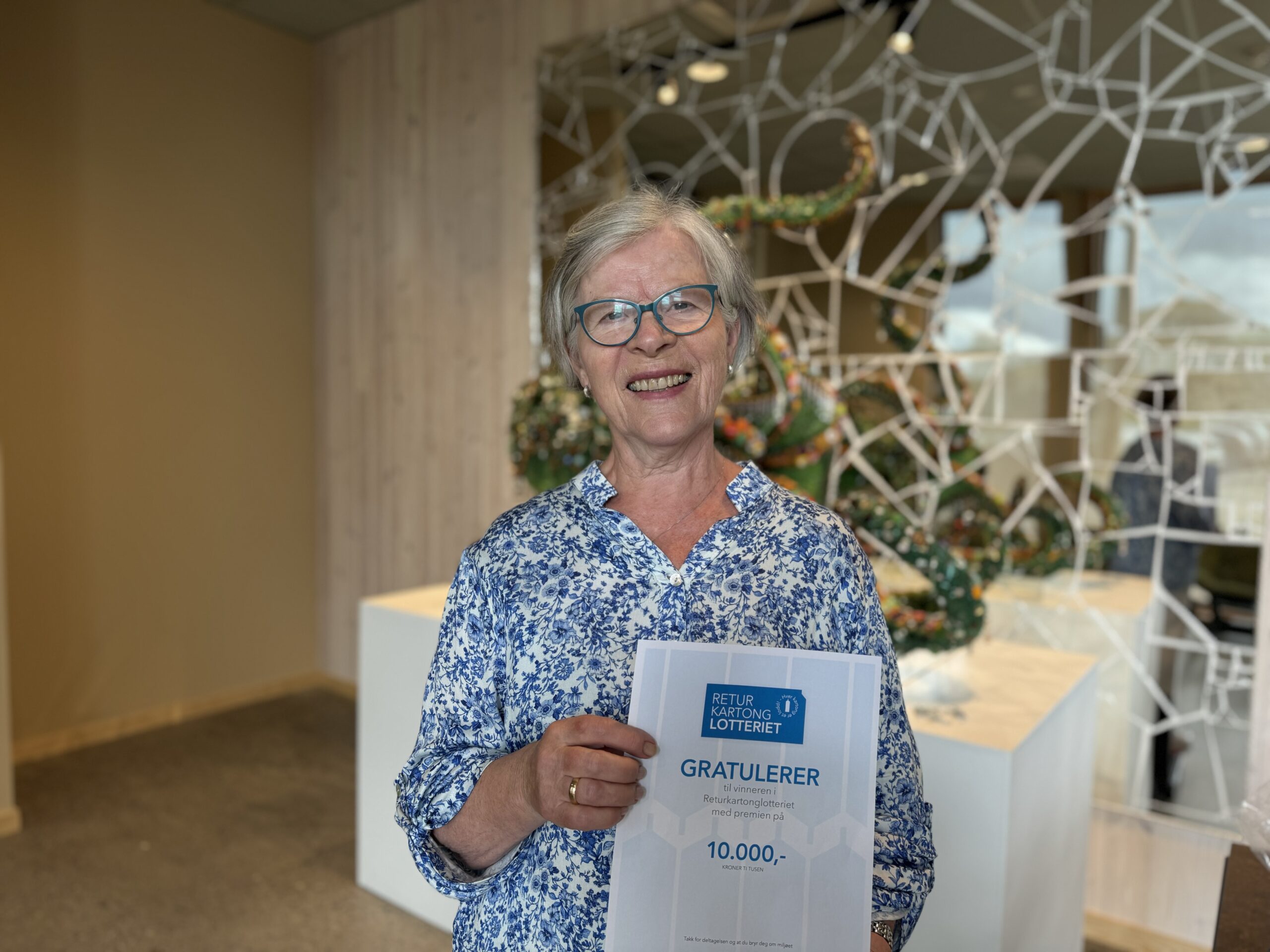 Vinner i Returkartonglotteriet, Berit Helene Krogstad, avbildet hos HIM. Hun holder et diplom i hånden.