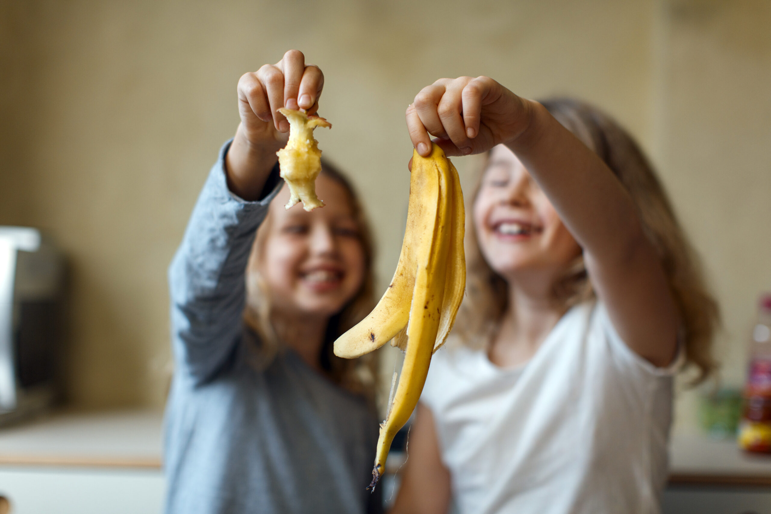To jenter holder frem en epleskrott og et bananskall