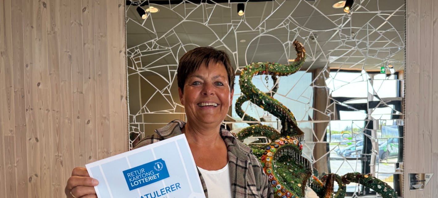 Tove Førre, vinner av Returkartonglotteriet, står i foajeen til HIM med diplomet som viser at hun er 10 000 kroner rikere